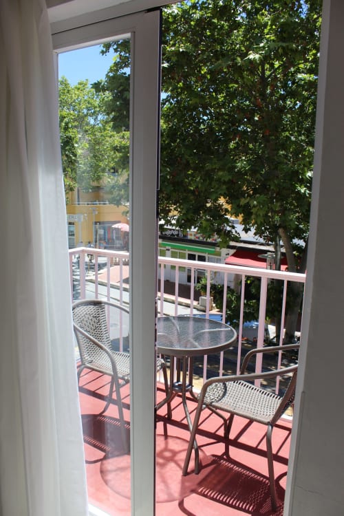 Vista del balcón de la habitación Villa Palmer en Paguera con mesa de comedor, sillas y frondosos árboles arriba