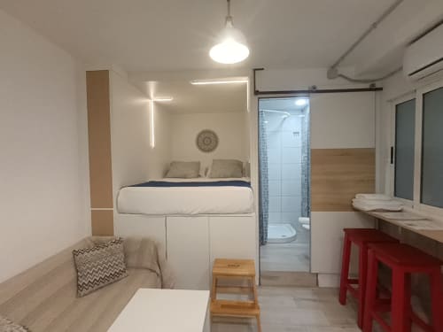 Estudio compacto en Sevilla con cama elevada, zona de estar, cocina americana y baño privado
