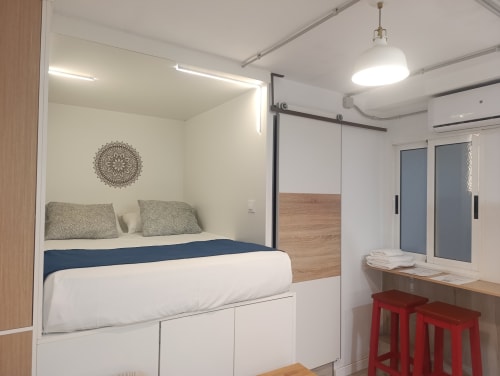 Moderno dormitorio en apartamento El Rincón de Sevilla con cama queen, almacenaje integrado, arte mandala y escritorio con rojo
