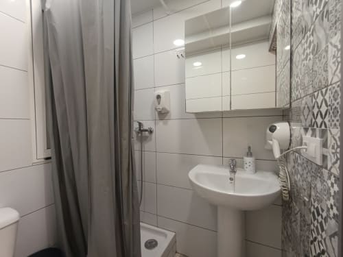 Baño moderno del apartamento El Rincón de Sevilla en Sevilla, España con azulejos blancos, lavabo de pedestal y ducha gris