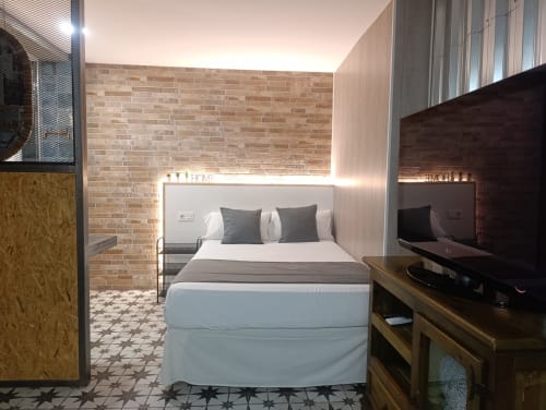 Dormitorio moderno en apartamento El Rincón de Sevilla con pared de ladrillo, televisor de pantalla plana y decoración contemporánea