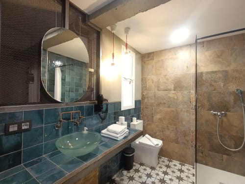 Baño moderno en apartamento El Rincón de Sevilla con azulejos turquesa, lavamanos verde, ducha abierta y suelo geométrico