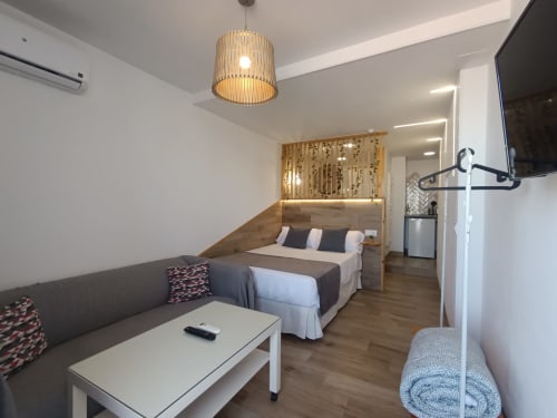 Moderno apartamento estudio en Sevilla con cama, sofá, cocina americana, TV de pantalla plana e iluminación colgante