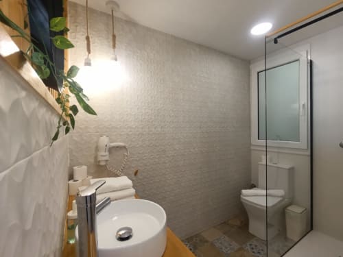 Baño moderno en apartamento El Rincón de Sevilla con lavamanos redondo, ducha de cristal, inodoro y paredes con textura decorativa