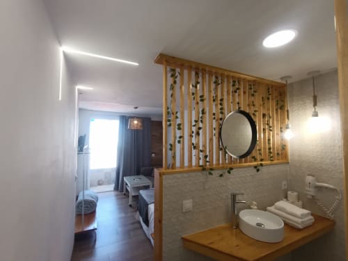 Baño moderno del apartamento El Rincón de Sevilla con espejo redondo, tocador de madera y biombo decorativo de madera