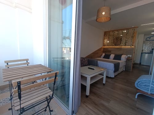 Estudio en Sevilla con sala abierta, cama, cocina americana y balcón con vistas a la ciudad