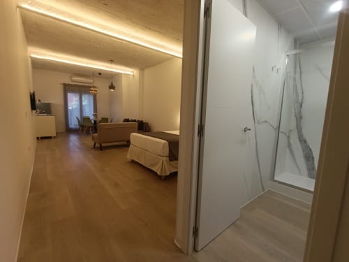 Apartamento moderno en El Rincón de Sevilla con sala de estar, sofá, suelos de madera y entrada al baño con ducha