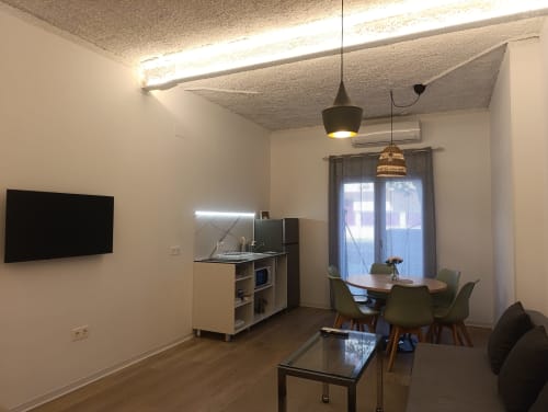 Moderna zona de estar en El Rincón de Sevilla con cocina, mesa de comedor, TV mural e iluminación colgante