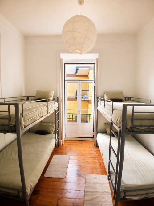 Quatro camas beliche num quarto de dormitório limpo e minimalista do Grupo Lisboa Alojamentos em Lisboa com piso de madeira