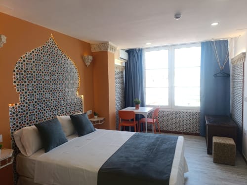 Dormitorio moderno en El Rincón de Sevilla con cabecero de patrón islámico ornamentado, pared acentuada en naranja, cortinas azules