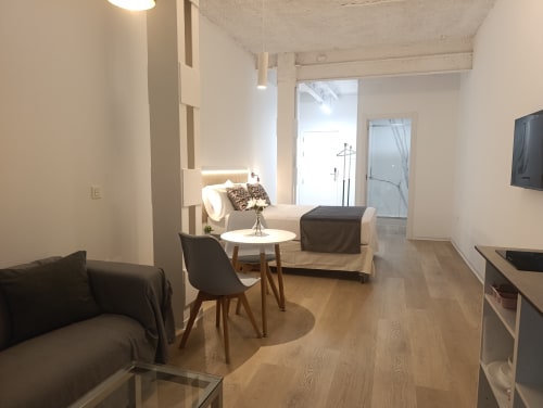 Apartamento moderno en El Rincón de Sevilla con sala abierta, sofá beige, silla negra, pisos de madera y televisor plano