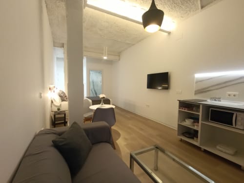 Sala de estar moderna en El Rincón de Sevilla con sofá, cocina, televisor y mobiliario contemporáneo