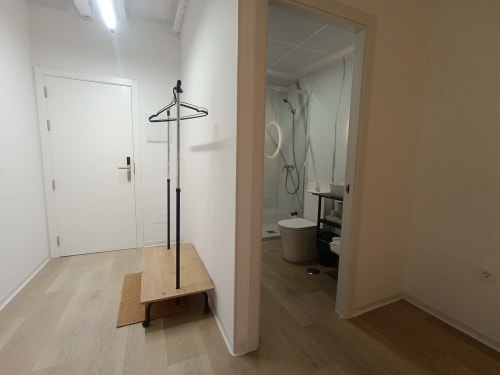 Pasillo de entrada del apartamento El Rincón de Sevilla con perchero, baño visible a la derecha y pisos de madera