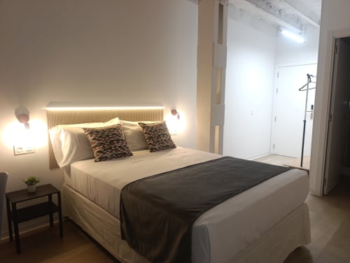 Dormitorio moderno en El Rincón de Sevilla con cabecero iluminado, almohadas estampadas y manta negra en apartamento de Sevilla