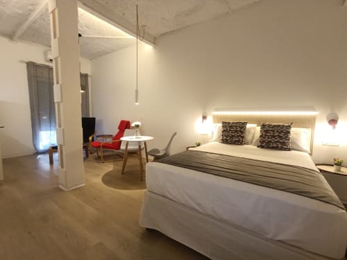Dormitorio moderno del apartamento El Rincón de Sevilla con cama, sillón rojo y zona de estar en Sevilla, España