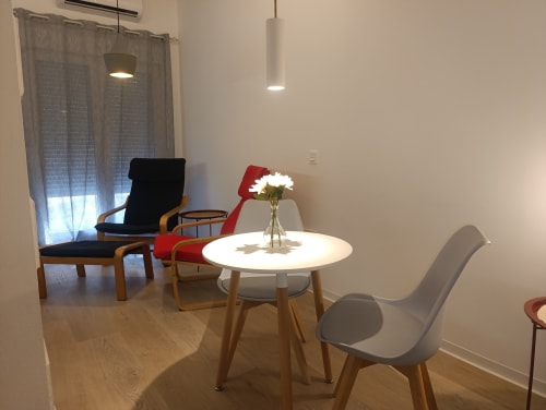 Elegante sala de estar en El Rincón de Sevilla con mesa redonda blanca, sillas coloridas e iluminación colgante cerca de Sevilla