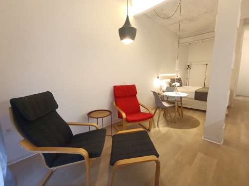 Sala moderna en El Rincón de Sevilla con silla negra, silla roja, puf y decoración minimalista en apartamento luminoso