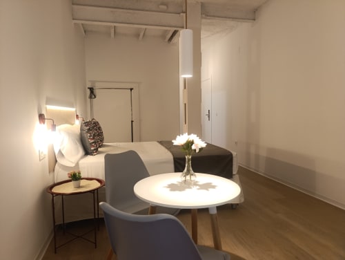 Habitación moderna del apartamento El Rincón de Sevilla en Sevilla con cama, mesa redonda blanca, silla e iluminación contemporánea