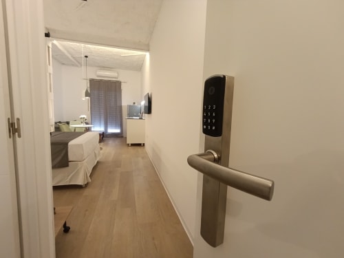 Cerradura digital en la entrada del apartamento El Rincón de Sevilla, vista del pasillo hacia el dormitorio con muebles modernos