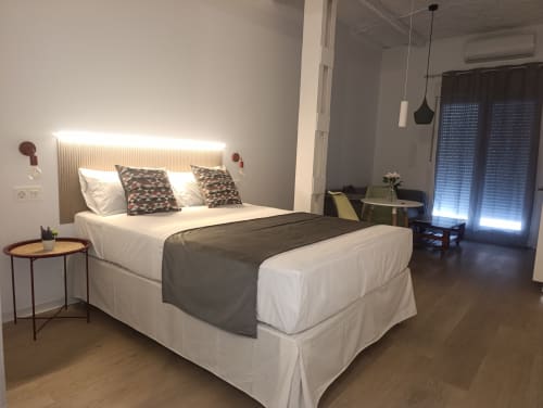 Dormitorio moderno en El Rincón de Sevilla con cabecero iluminado, cama blanca, almohadas estampadas y acceso a terraza