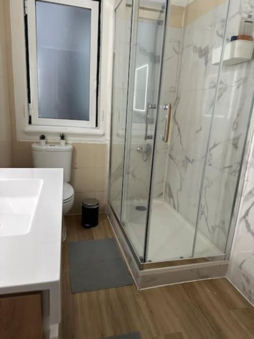Banheiro moderno no albergue Grupo Lisboa Alojamentos com box de chuveiro, vaso sanitário, pia e piso em madeira em Lisboa