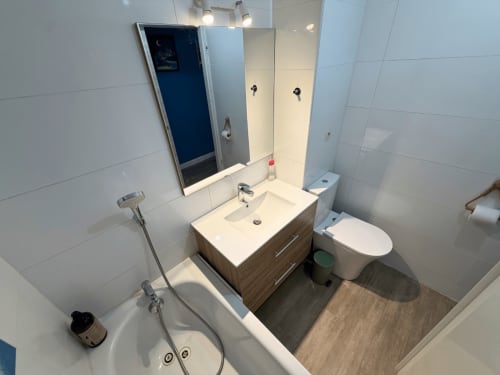 Modern bathroom at Horizon Doré hotel in Gourbeyre with vanity sink, toilet, mirror, and bathtub with shower fixtures