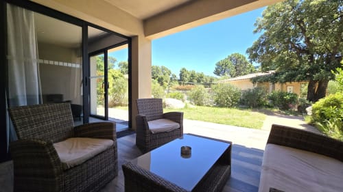 Moderner Patio in der Villas Lantana in Lecci mit Rattanmöbeln, blauem Couchtisch und Gartenblick aus dem 2-Zimmer-Apartment
