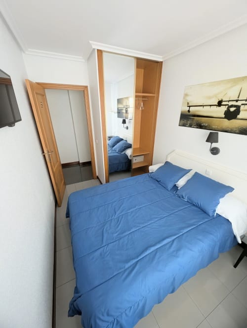 Habitación doble en La Ballena B&B en Santoña con ropa de cama azul, puertas de madera y televisor