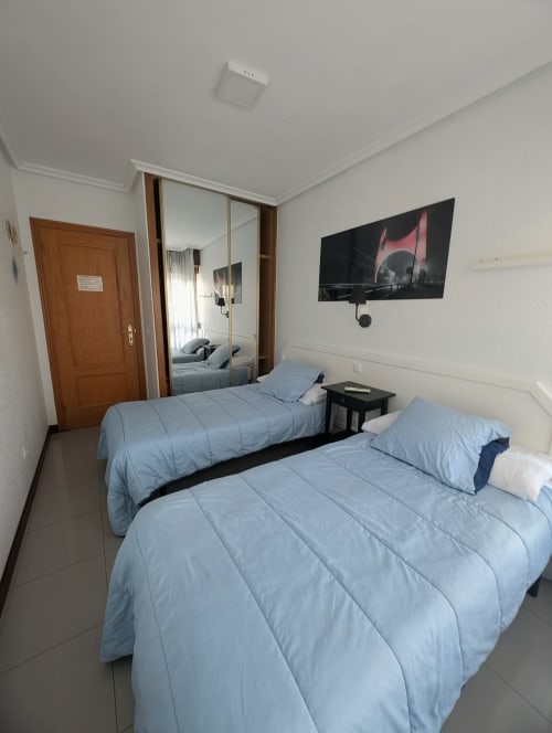 Habitación doble con dos camas individuales, TV y armario espejado en Alojamiento La Ballena, Santoña