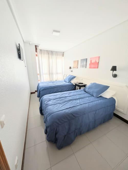 Dos camas individuales con ropa de cama azul en luminosa habitación doble de La Ballena B&B, Santoña, con baño compartido y vistas a la ciudad