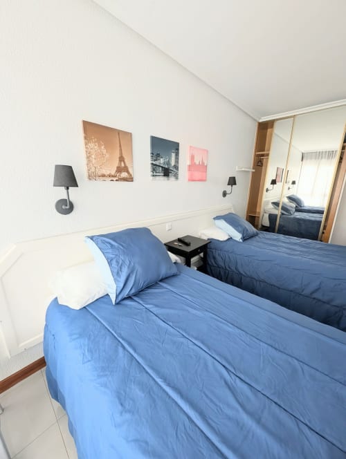 Habitación doble con dos camas azules y baño compartido en La Ballena B&B de Santoña, con vistas a la ciudad y arte mural