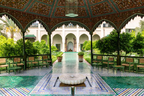 Palais Talilit courtyard in Marrakech featuring ornate zellige tilework, green carved archways, and traditional Moroccan