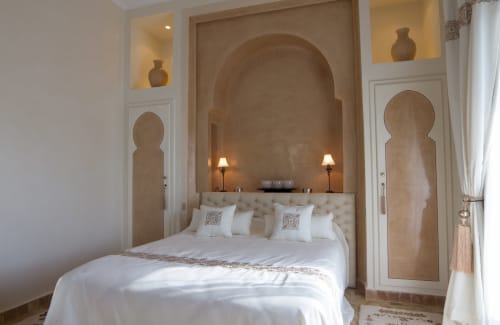 Aknaria bedroom at Palais Talilit, Marrakech with arched alcove, tufted headboard, white linens