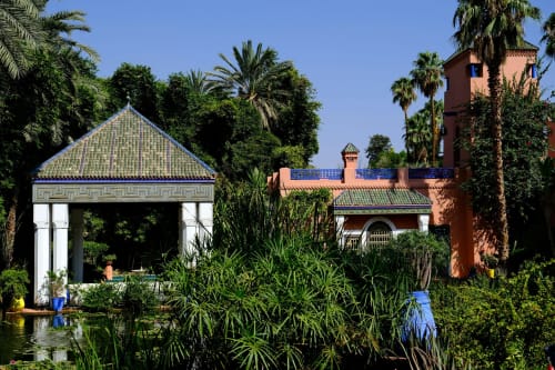 Palais Talilit garden pavilion with green-tiled roof, terracotta buildings, palm trees in Marrakech