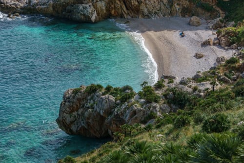 Cala turchese con spiaggia sabbiosa e scogliere rocciose vicino a San Vito Lo Capo, Sicilia