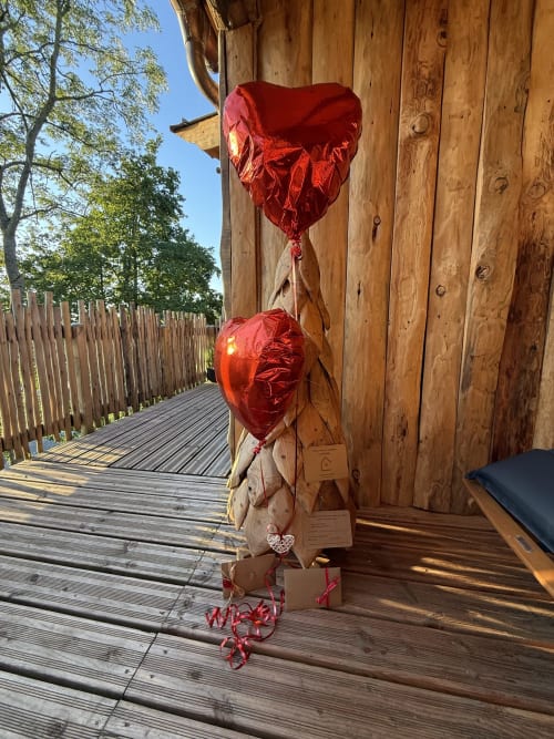 Deux ballons en forme de cœur rouge sur la terrasse en bois du Cœur de lodge, un gîte romantique à Cramoisy, France