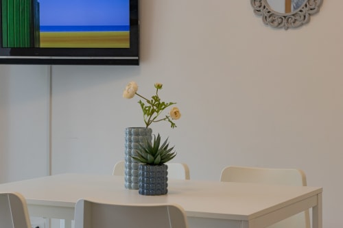 Dining area at Pescara INN Beach House with table, chairs, and fresh flowers in textured vase