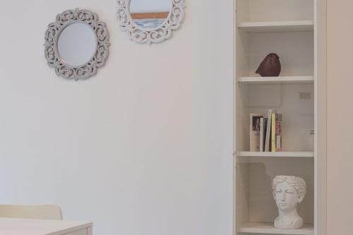 Modern shelving unit in Pescara INN Beach House apartment with decorative mirrors, books, and white bust sculpture