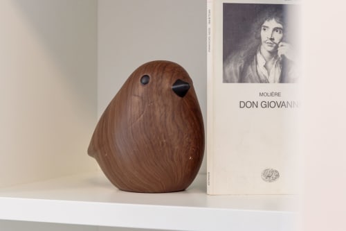 Wooden bird sculpture and Molière's Don Giovanni book on white shelf in Pescara INN Beach House apartment