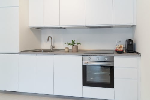 Modern white kitchen with built-in oven, sink, and gray countertops at Pescara INN Beach House in Pescara, Italy