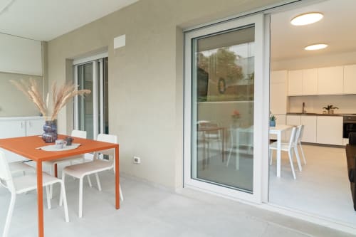 Modern dining area at Pescara INN Beach House with orange table, white chairs, garden view through large sliding doors