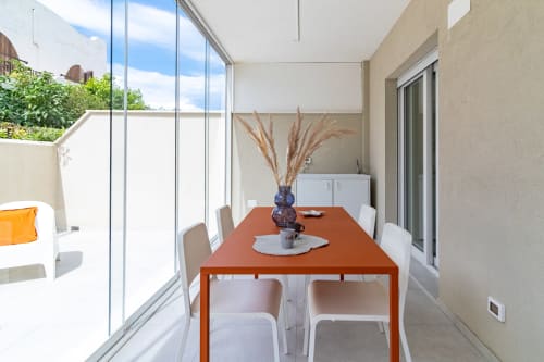 Modern dining area with orange table, white chairs, and garden views at Pescara INN Beach House