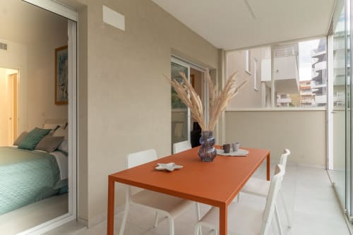 Modern dining area with orange table and white chairs at Pescara INN Beach House, overlooking balcony