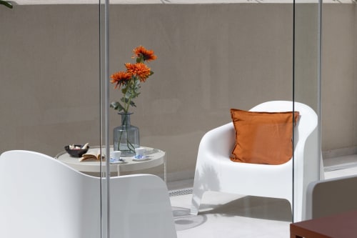 Modern white armchair with orange cushion beside round table with fresh orange gerberas at Pescara INN Beach House apartment