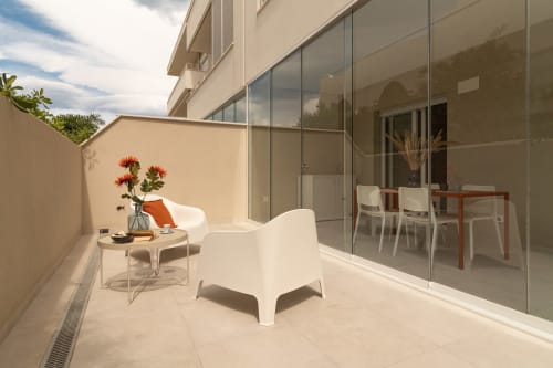 Modern terrace at Pescara INN Beach House with white chair, potted flowers, glass doors opening to dining area, and beige