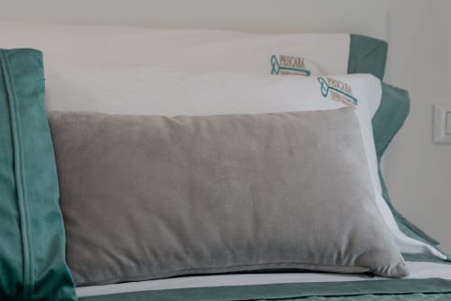 Gray pillow with Pescara INN branding on white bedding in Beach House apartment room
