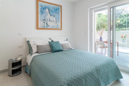 Modern bedroom at Pescara INN Beach House with teal bedding, garden view doors, framed artwork, and contemporary furnishings