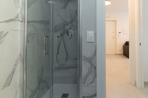 Modern shower enclosure with marble-pattern glass panels at Pescara INN beach apartment in Italy