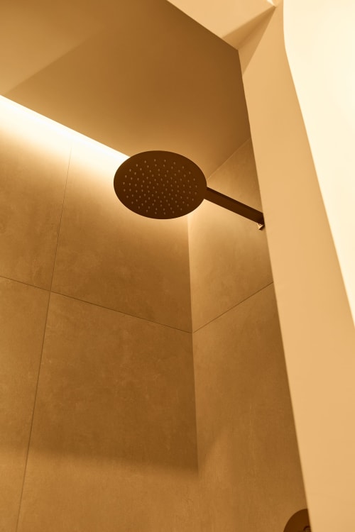 Modern overhead shower fixture mounted on beige tiled bathroom ceiling in Arrels Mercat apartment, Valencia