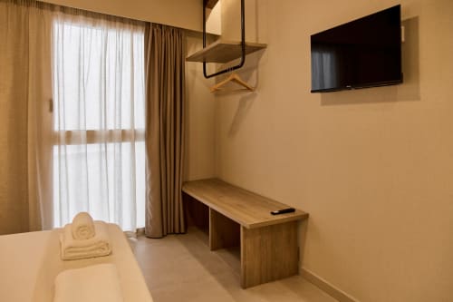 Modern apartment bedroom at Arrels Mercat Valencia with wooden desk, wall-mounted TV, and floor-to-ceiling windows with